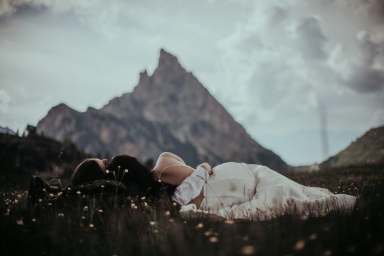 wedding couple laying in the meadows of the Dolomites